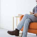 Grace Therapy and Wellness Center man sitting on orange couch on phone
