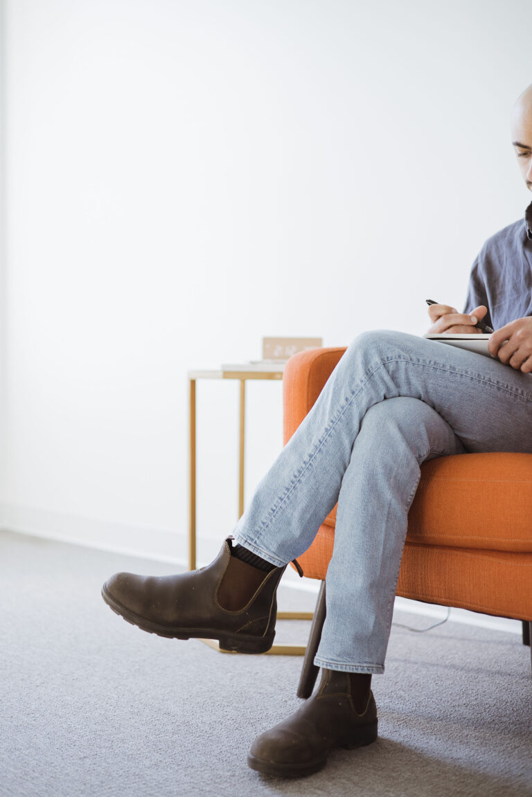 Grace Therapy and Wellness Center man sitting on orange couch on phone