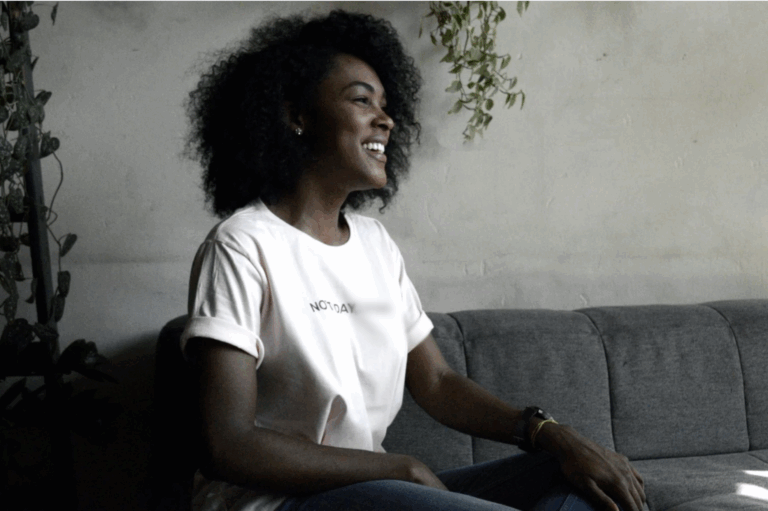 black woman sitting on couch smiling - gtwc person centered therapy