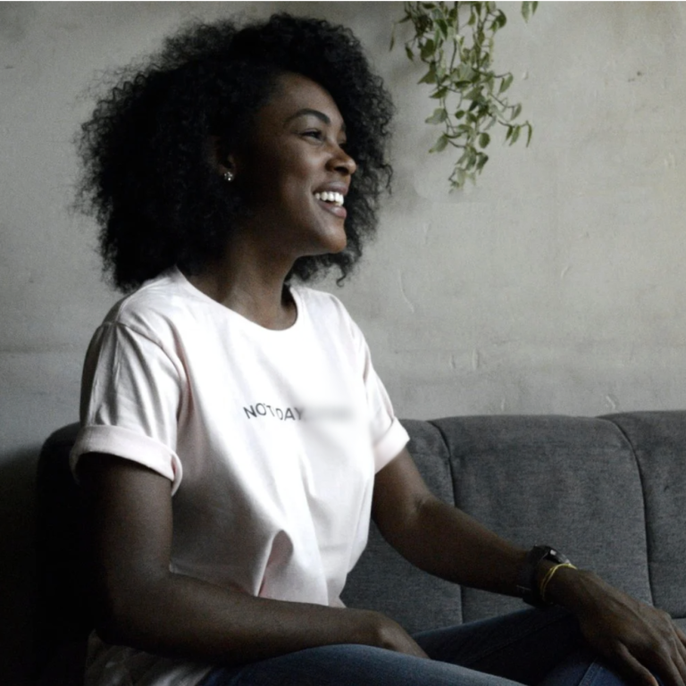 black woman sitting on couch smiling - gtwc person centered therapy